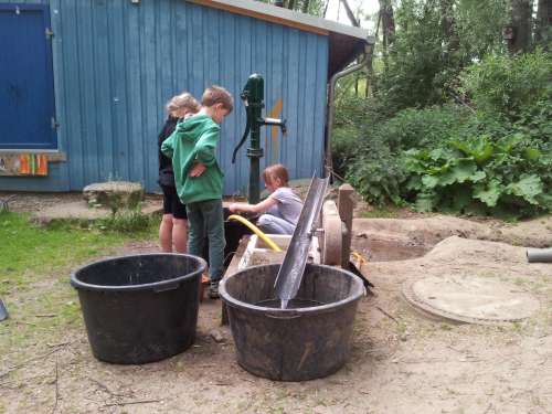 Abenteuerspielplatz Lernziel Spielen - Wasser wird an der Pumpe geholt