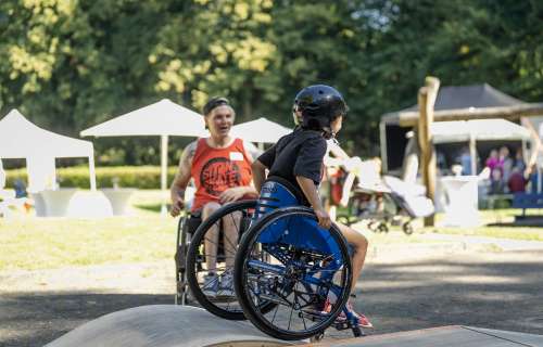 David Lebuser zeigt einen Kind, wie man den Rollstuhl beherrscht.