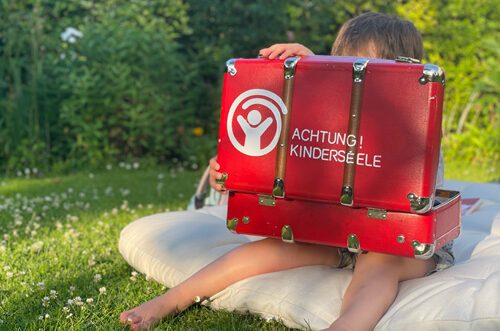Kind mit dem Patenkoffer Achtung Kinderseele