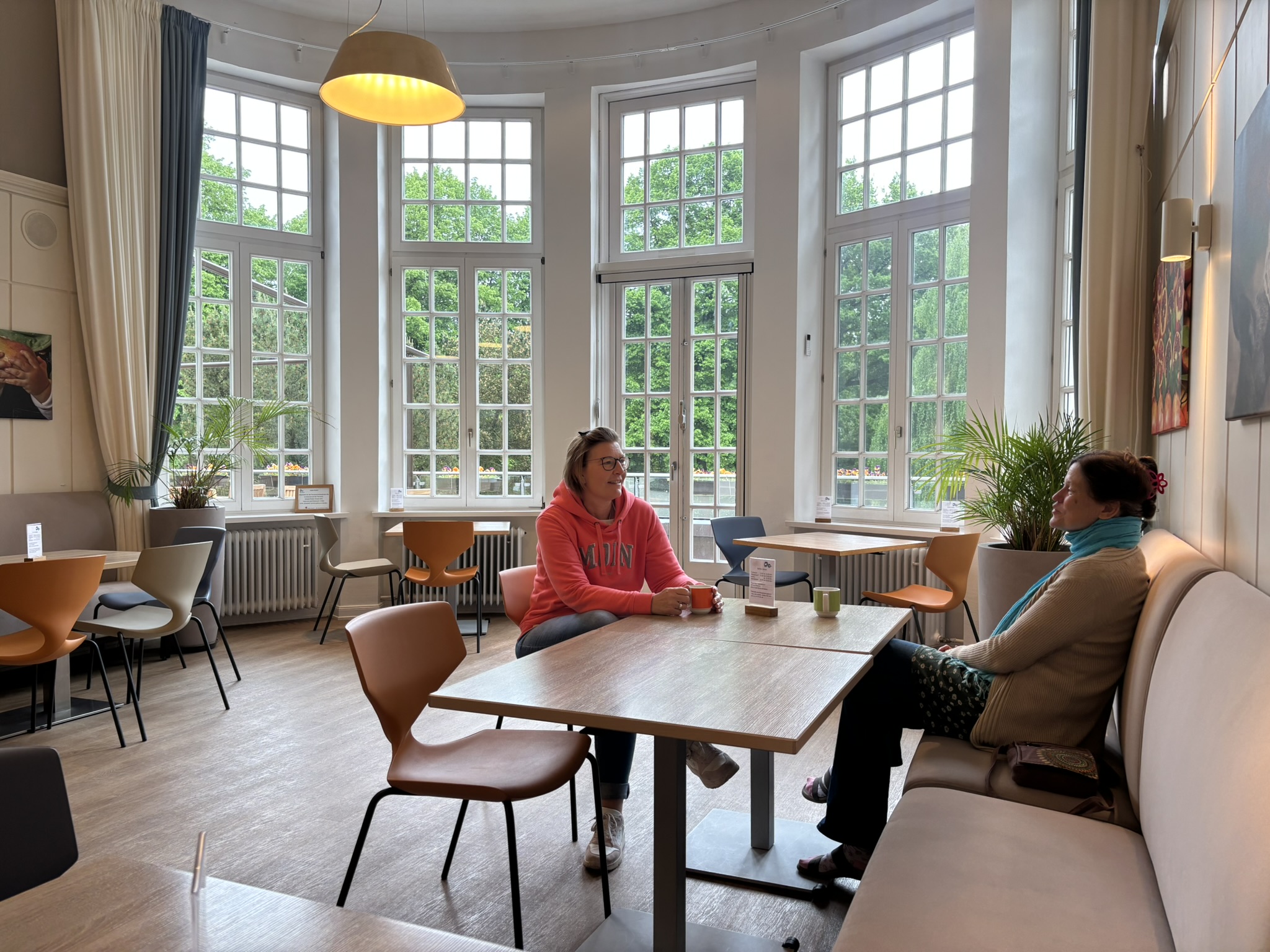 Zwei Frauen sitzen sich an einem Tisch gegenüber und sprechen miteinander. Sie sitzen in einem hellen, offenen Raum.