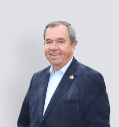 Portraitfoto von Person, die lächelnd in die Kamera schaut, neutraler Hintergrund.
