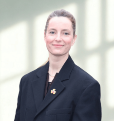 Portraitfoto einer jungen Frau mit zurückgebundenen Haaren und dunklem Sakko